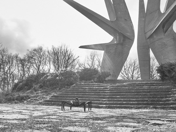 Host Guest hexapod robot at base of brutalist monument